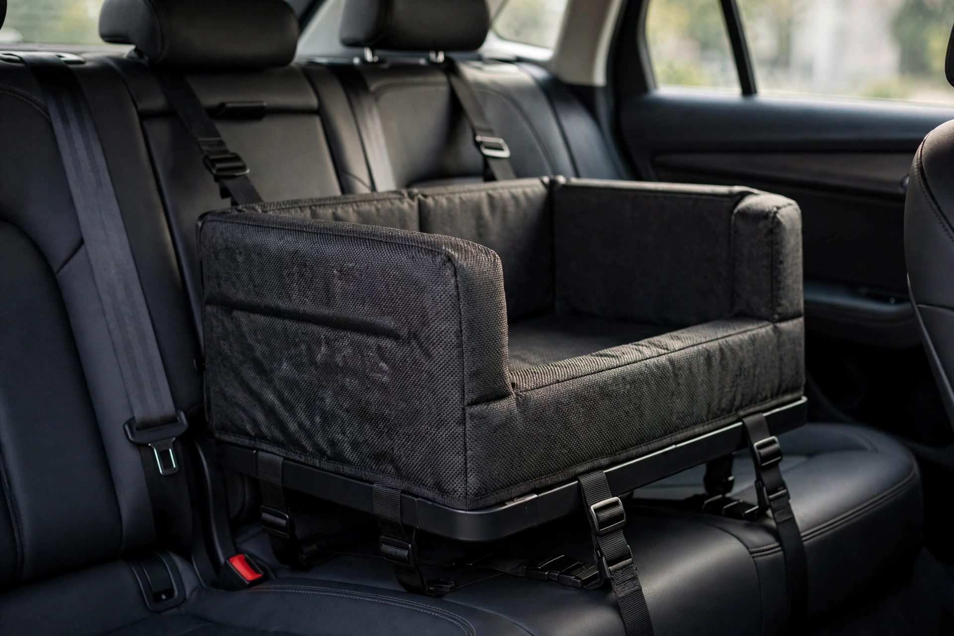 Wuglo Extra Stable Dog Car Seat in black, strapped into a car back seat